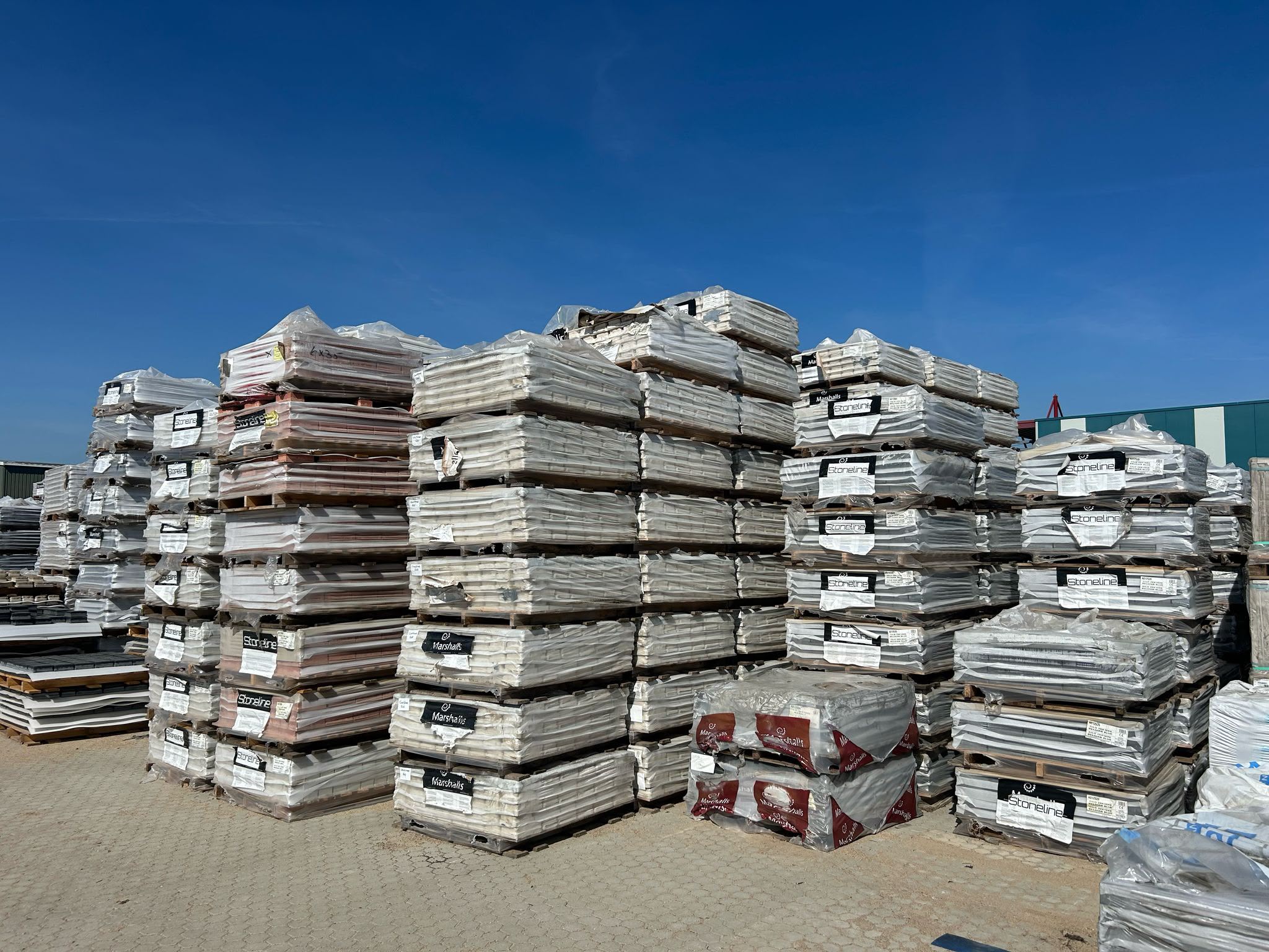 Partijen tegels op pallets, waaronder de merken Stoneline en Marshalls, bij DB Trading