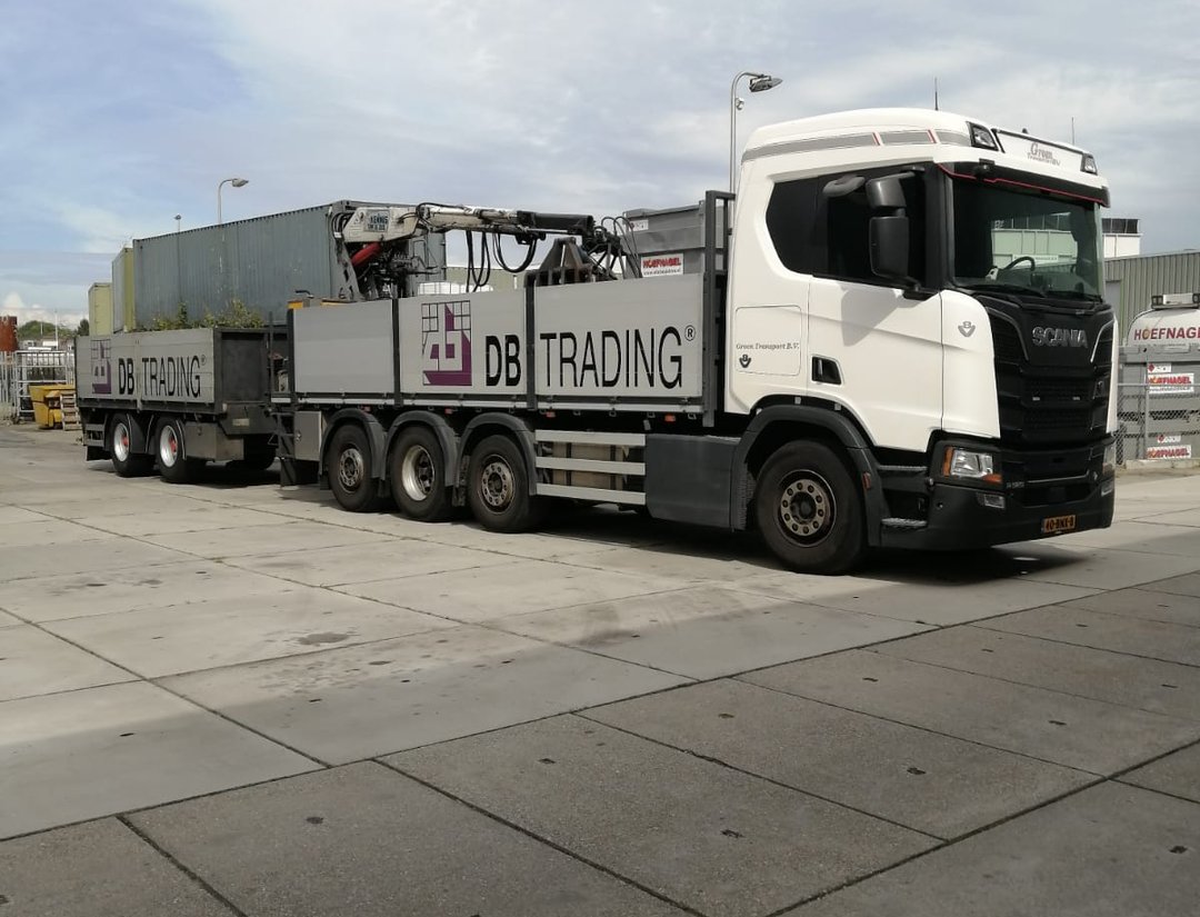 Vrachtwagen met laadkraan van DB Trading, beladen met sierbestrating en gereed voor levering